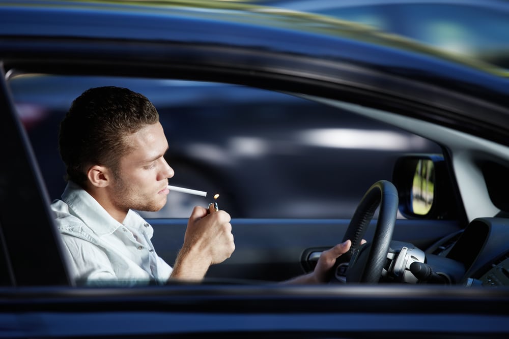 A young man lit a cigarette in a car at speed